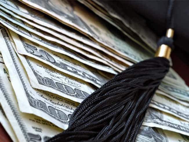 Image of tassle from cap sitting on top of some money